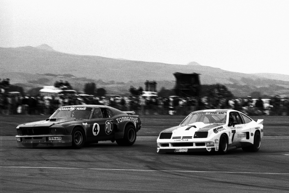 Wigram 1976. Leo Leonard PDL1 Mustang and Allan Moffat Chev Monza both over commit and skate down the escape road during a monumental battle. IMAGE/terry marshall