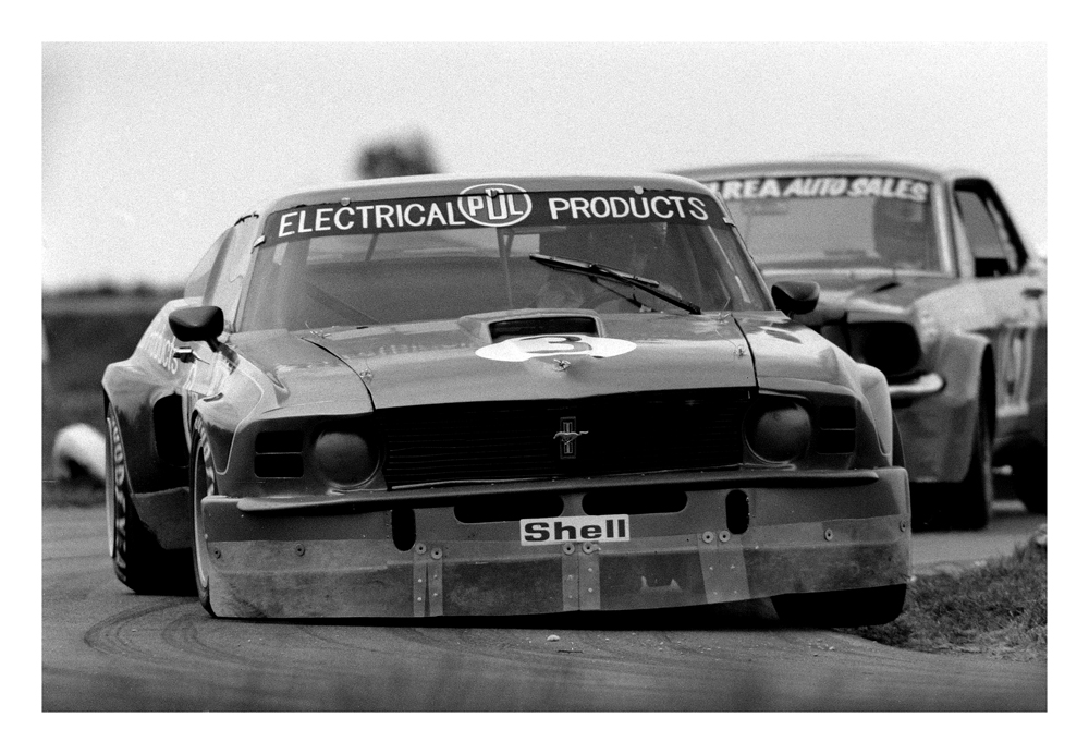 Timaru Motor Raceway 1977. Dave Baker giving the Electric Blue PDL1 Mustang and airing. Here leading Rod McElreas Mustang. The car previously raced by Paul Fahey. IMAGE/terry marshall