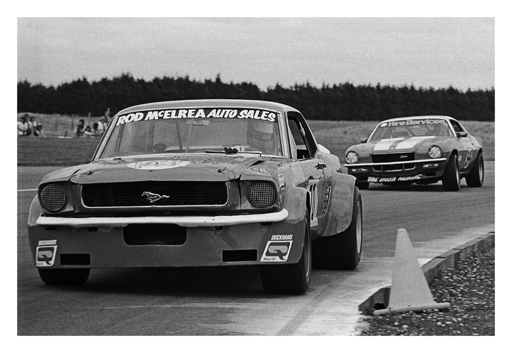 Wigram 1975. The legendary Rod McElrea hustles his OSCA Ford Mustang thru Bomb Bay corner. Following is Dave Bakers Z28 Camaro. IMAGE/terry marsha